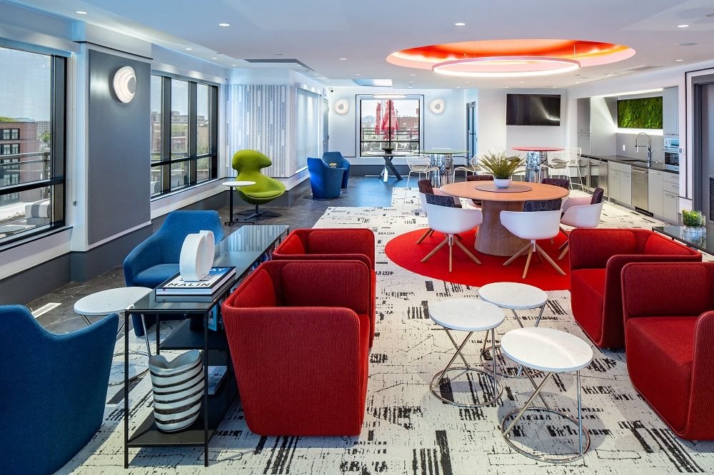 a lounge area with chairs and tables and a large window